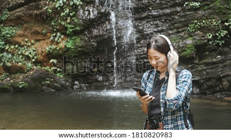 Young woman tourist traveling backpack enjoying adventure exploring nature jungle trail tracking into forest reaching using headphone  listening to music, outdoor freedom lifestyle.selective focus.