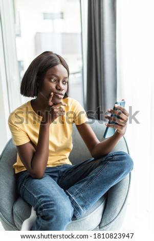 technology and people concept - smiling african american woman in glasses with smartphone at home