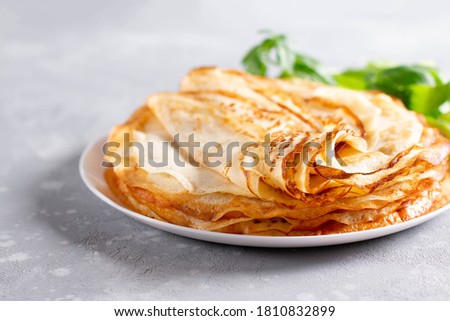 Thin homemade pancakes. Light background. Beautiful and delicious breakfast at home or in the cafe. Selective focus Royalty-Free Stock Photo #1810832899