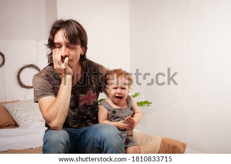 The child is screaming, hysterical. A tired dad doesn't want to hear the baby. The parent is irritated, tired, wants to take a break from his daughter. children's hysteria. Royalty-Free Stock Photo #1810833715