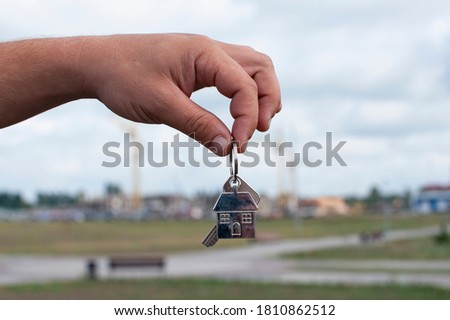 Guy holds the keys to the house in his hands against the background of the construction of apartments. Concept on the topic of buying a new home