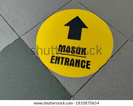 A round yellow entry sign on the floor, tanda one way di jalan aspal tanda untuk sati jalur masuk bagi pejalan kaki, dengan cat dasar warna kuning