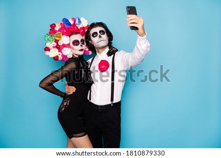 Photo of spooky monster couple man lady embrace hold telephone make theme selfie picture wear short mini black dress death costume roses headband suspenders isolated blue color background
