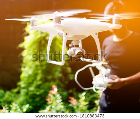 Asian man controlling drone flying by remote controller, Male using the his thumb operating the way for drone by monitor smart phone