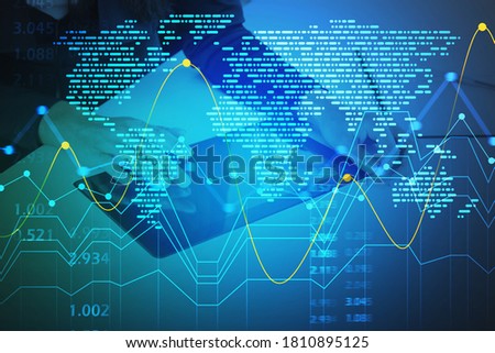 Top view of businessman using tablet at blurry office table with double exposure of world map hologram and graph. Toned image
