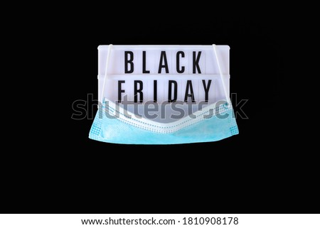 Black Friday sale text on white lightbox and protective face mask on black background. Black Friday sign with disposable medical mask. Thanksgiving promotion advertising