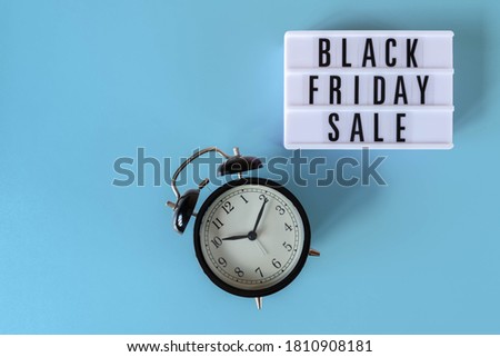 Black Friday sale text on white lightbox and alarm clock on blue background. Thanksgiving promotion advertising. Black Friday sign with copy space.