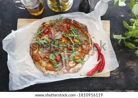 Italian pizza with ham. Traditional Italian pizza with Parma ham, cherry tomatoes and arugula.