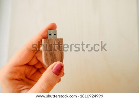Female hand holds a stylish wooden flash drive on a light background. beautiful photo feedback to the client. set for the photographer, presentable of photos, luxury
