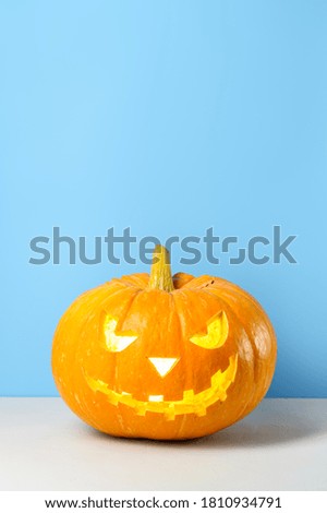 Glowing Halloween pumpkin on a pastel blue background. Space for text, vertical orientation