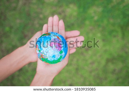 Hand woman holding earth on blur image of grass. Environmental conservation Earth Day concept.