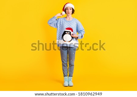 Full length photo of attractive funny lady touch her x-mas santa hat pompon jumper cute penguin check difference fluffy wear ugly ornament sweater jeans boots isolated yellow color background