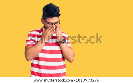 Handsome latin american young man wearing casual clothes and glasses rubbing eyes for fatigue and headache, sleepy and tired expression. vision problem 