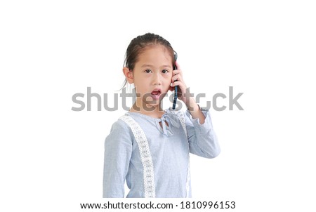 Excited Asian little child girl talking mobile phone and looking at camera isolated on white background.
