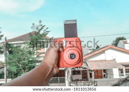 Human hands holding a camera with a blue sky background