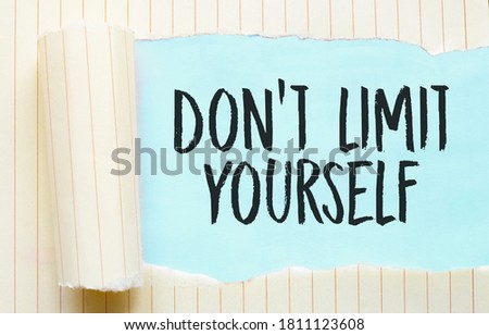 The text DONT LIMIT YOURSELF appearing behind torn white paper