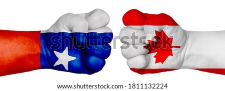 The concept of the struggle of peoples. Two hands are clenched into fists and are located opposite each other. Hands painted in the colors of the flags of the countries. Canada vs Chile