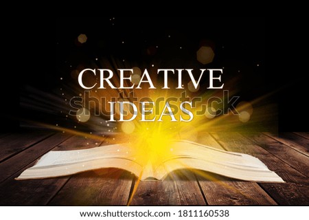 CREATIVE IDEAS inscription coming out from an open book, educational concept