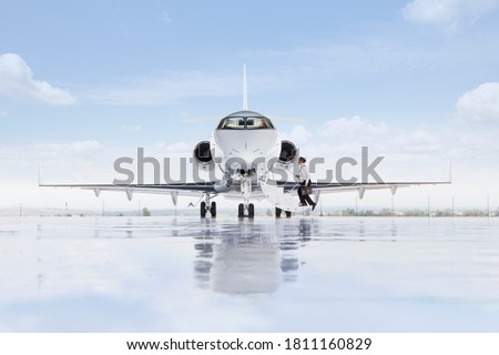 A wide shot of pilot boarding a private jet on a runway. Royalty-Free Stock Photo #1811160829