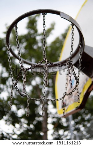 Close up of basketball hoop with metal chain net and yellow backboard in a street basketball court at the park