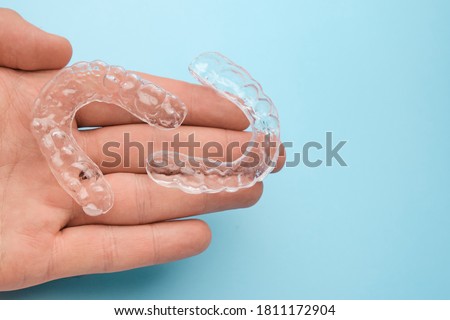 Ortodontist holding in his hand invisible or transparent removable braces fro teeth correction and whitening with copy space. Royalty-Free Stock Photo #1811172904