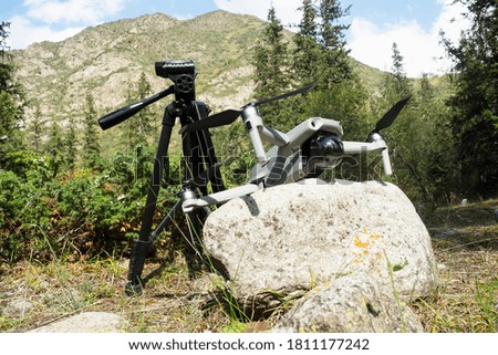 Photo equipment (tripod, drone) on a colorful summer background of mountains, juniper.