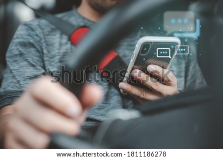 Man Texting while driving car. Irresponsible man Chatting and using smartphone. Writing and typing message with cellphone in vehicle. Holding steering wheel with other hand. Royalty-Free Stock Photo #1811186278