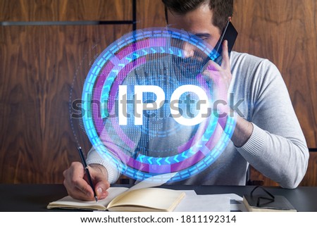Handsome analyst in casual long sleeve talking phone, taking notes at office workplace try to analyze IPO project. Double exposure. Initial public offering hologram. Royalty-Free Stock Photo #1811192314