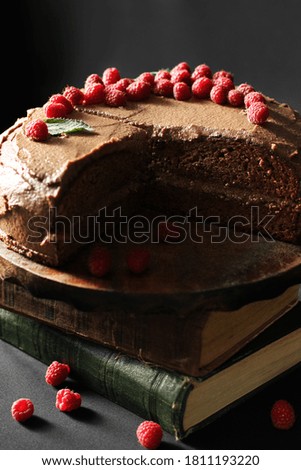 Prague cake. Chocolate cake with raspberries and books. Cake on a dark background.