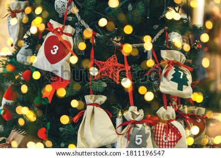 Various Christmas tree toys including star and gift bags on the Christmas tree. Festive background with many lights.
