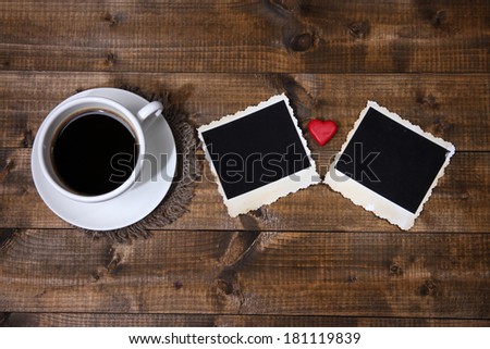 Composition with coffee cup, decorative hearts and old blank photos, on wooden background