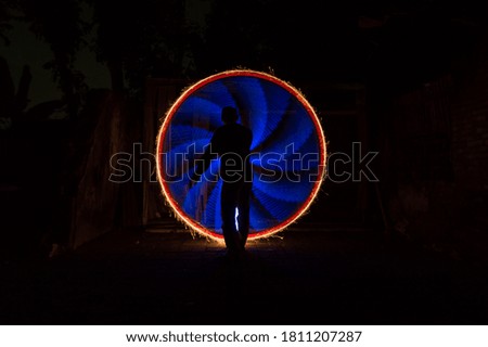 One people standing alone against a incredible of circle light painting as the backdrop