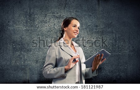 Young pretty businesswoman against grey background using tablet pc