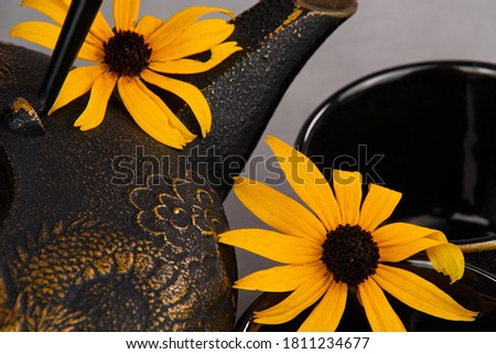 Closeup of a cast iron teapot accented with daisies