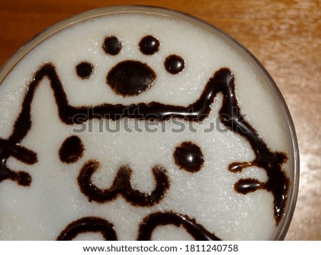 Latte coffee decorated with chocolate sauce drawing of a cat.