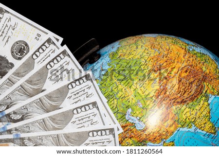 Dollar bills and globe on black background