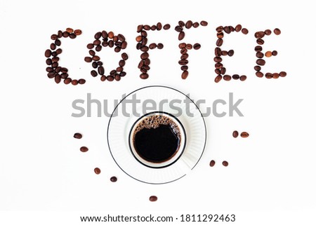 Top view of esspresso in white porcelain cup on saucer and inscription coffee from coffee beans on white background.
