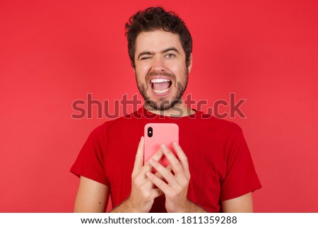 Portrait of Young handsome caucasian man wearing t-shirt over isolated red background, taking a selfie  celebrating success