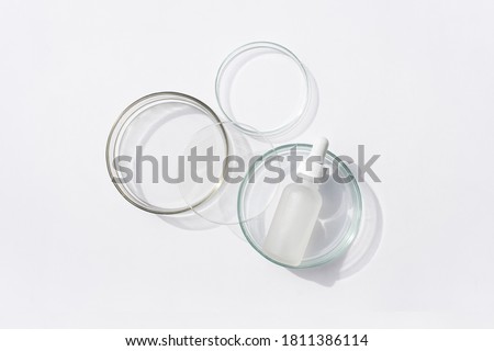 Glass bottle in petri dish on white background. Top view, flat lay. Concept skincare. Dermatology science cosmetic laboratory. Natural medicine, cosmetic research, organic skin care products.  Royalty-Free Stock Photo #1811386114