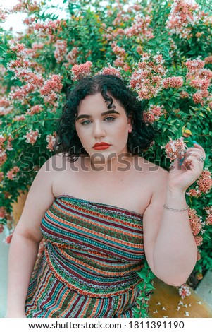 Caucasian Woman Posing in front of flower bush.
