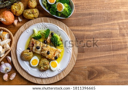 Cod loin baked in olive oil, with potatoes, broccoli, boiled egg and black olives. Typical dish of Portugal. Top view. Space for text.