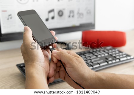Close up hand a man use USB cable connect to the computer desktop transfer data and music file to smartphone