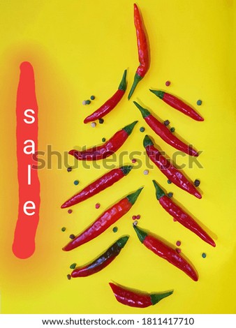 Red chili and peppercorns on a yellow background. Inscription letters SALE. Sale inscription on the photo.