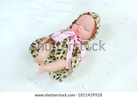 toy baby doll in clothes with a leopard print on a white background