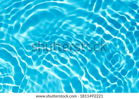 Blurred transparent blue colored clear calm water surface texture with splashes and bubbles. Trendy abstract nature background. Water waves in sunlight with copy space.