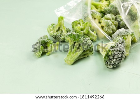 Frozen broccoli spilled out of a plastic bag. Light background with copy space. Selective focus Royalty-Free Stock Photo #1811492266