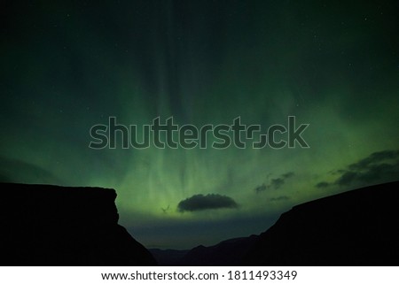 Aurora borealis against the silhouette of mountains and night sky