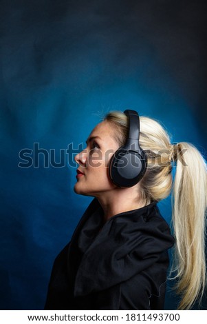 Blonde with headphones. sideways. Photography in the studio, dark background.