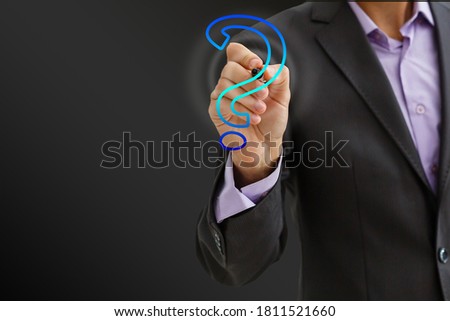 Businessman on blurred background touching hand drawn question marks with his fingers