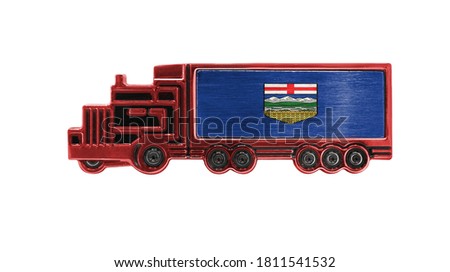 Toy truck with Alberta flag shown isolated on white background. The concept of cargo transportation between countries.